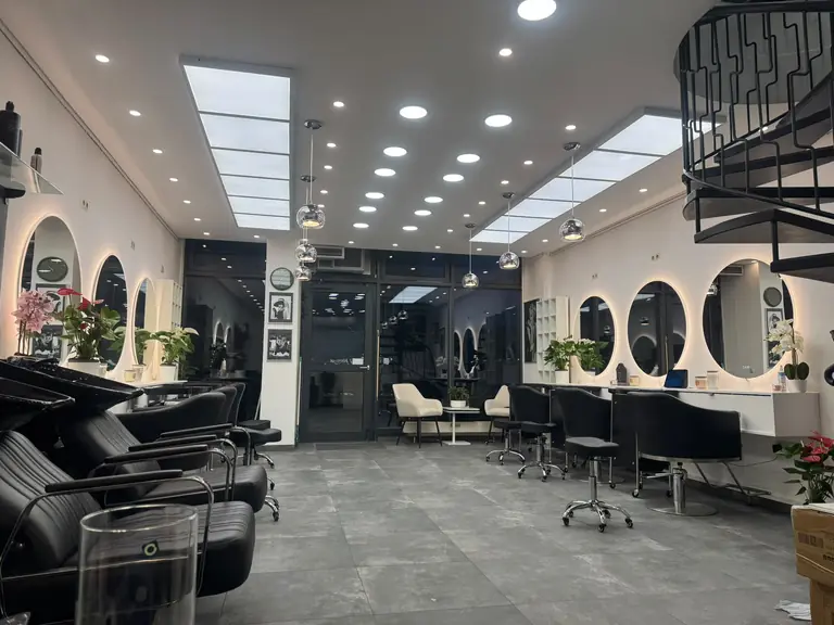 Abendstimmung im Salon: Waschplätze, Bedienplätze mit Rundspiegeln und Sessel an der Fensterfront zur Steinsdorfstraße