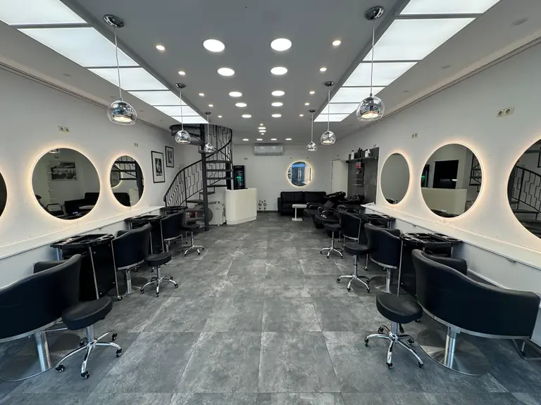 Blick durch den Friseursalon IsarBella Hair & Beauty in München Lehel mit runden, beleuchteten Spiegeln und Wendeltreppe