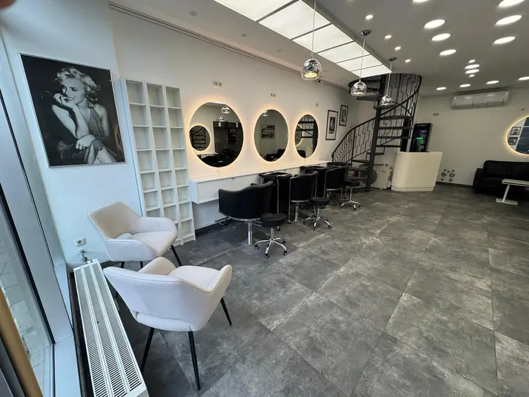 Schneideplätze mit beleuchteten Rundspiegeln und Wartebereich im Friseursalon in München Lehel